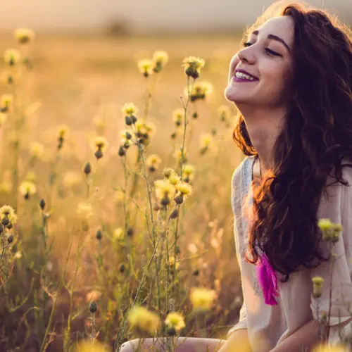 Achtsame Auszeit: Frau genießt still den Moment in einem Feld voller Blumen – Symbol für Ruhe, Rückzug und innere Einkehr beim Wochenend-Retreat