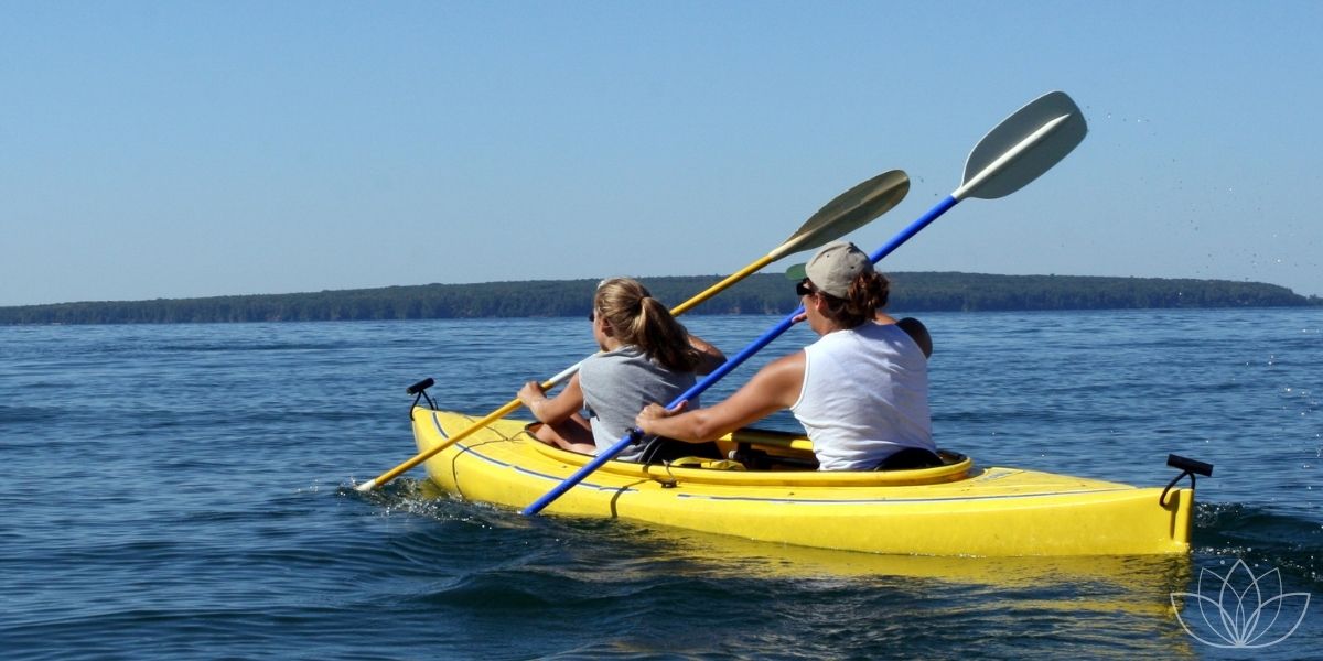 Partner rudern gemeinsam in einem Doppel-Kajak auf einem See