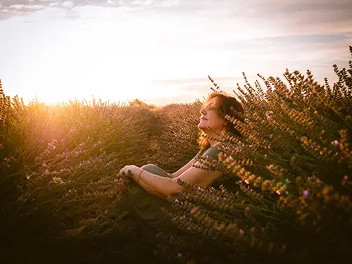 Frau sitzt auf einer Wiese im Sonnenuntergang